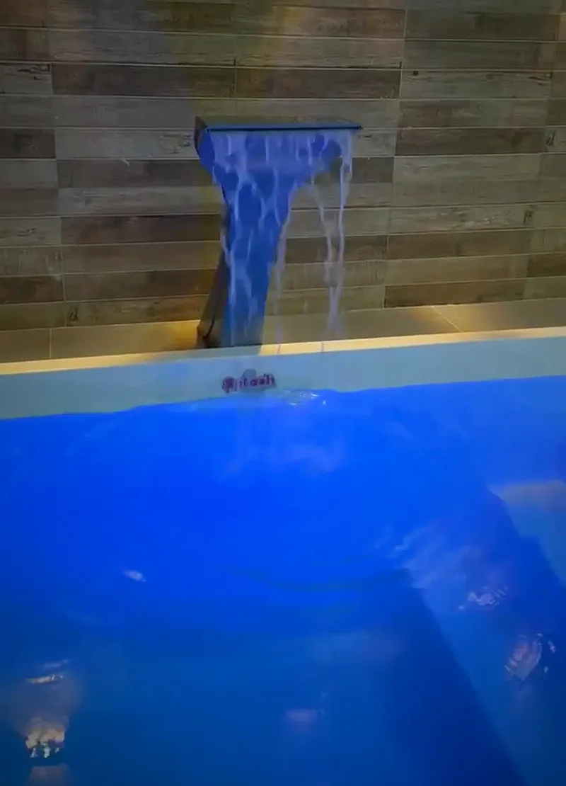 Cascata caindo na piscina iluminada